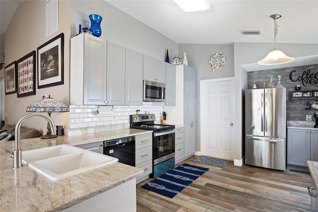 1145 Jaybee Ave, Davenport, FL 33897 - kitchen with appliances with stainless steel finishes, backsplash, light wood-style flooring, and hanging light fixtures