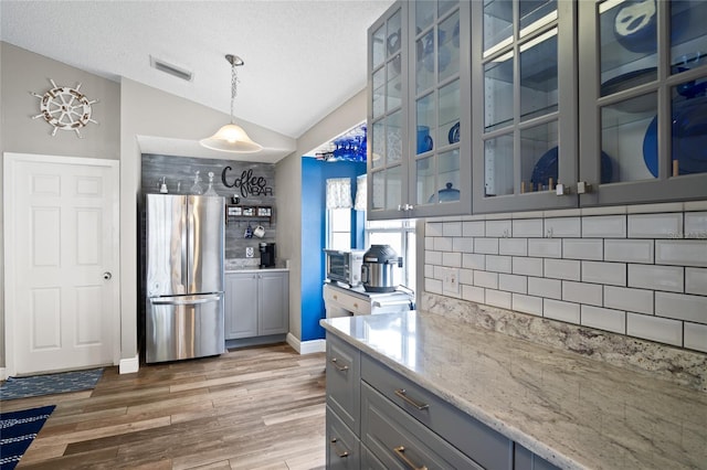 1145 Jaybee Ave, Davenport, FL 33897 - kitchen featuring freestanding refrigerator, gray cabinetry, vaulted ceiling, light wood-style flooring, and backsplash
