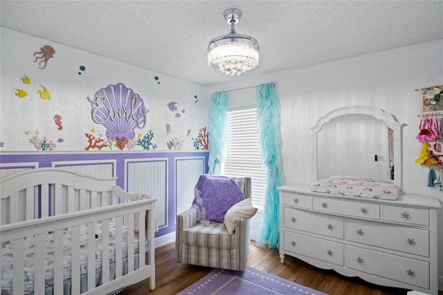 1145 Jaybee Ave, Davenport, FL 33897 - bedroom with a crib, a chandelier, a textured ceiling, and wood finished floors