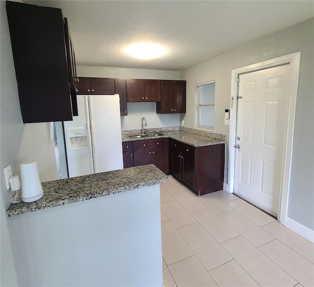 4118 Kirkland Blvd, Orlando, FL 32811 - kitchen with white refrigerator with ice dispenser, light stone countertops, a peninsula, light tile patterned floors, and dark brown cabinetry