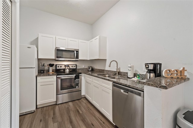 2786 Club Cortile Cir Unit B, Kissimmee, FL 34746 - kitchen with stainless steel appliances, white cabinetry, dark wood-type flooring, and dark stone counters