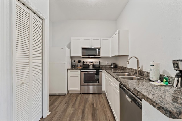 2786 Club Cortile Cir Unit B, Kissimmee, FL 34746 - kitchen with appliances with stainless steel finishes, white cabinetry, dark wood-style flooring, and dark stone counters