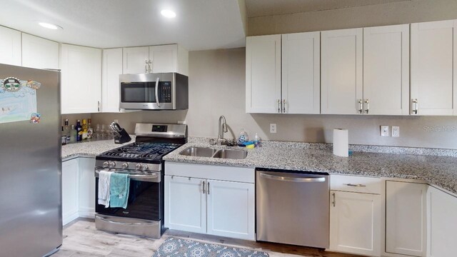 133 Oyster Bay Cir Unit 100, Altamonte Springs, FL 32701 - kitchen featuring stainless steel appliances, white cabinets, light wood finished floors, light stone countertops, and recessed lighting
