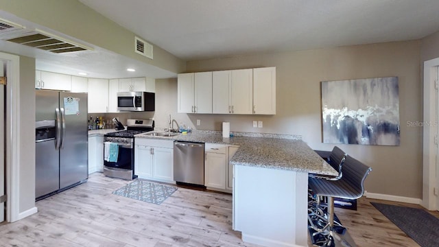 133 Oyster Bay Cir Unit 100, Altamonte Springs, FL 32701 - kitchen with stainless steel appliances, light wood finished floors, a peninsula, white cabinets, and recessed lighting