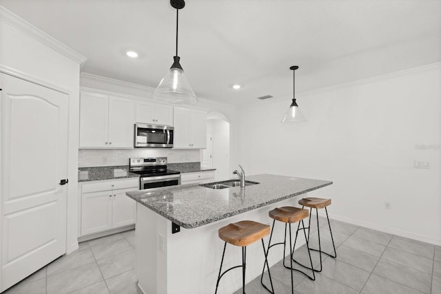 5684 Horseshoe Loop, Apopka, FL 32712 - kitchen featuring appliances with stainless steel finishes, arched walkways, ornamental molding, light tile patterned floors, and dark stone countertops