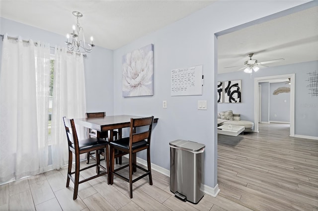 dining space with light wood-type flooring, a chandelier, and a ceiling fan