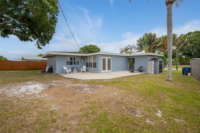 rear view of property featuring french doors, a patio area, a storage unit, and stucco siding