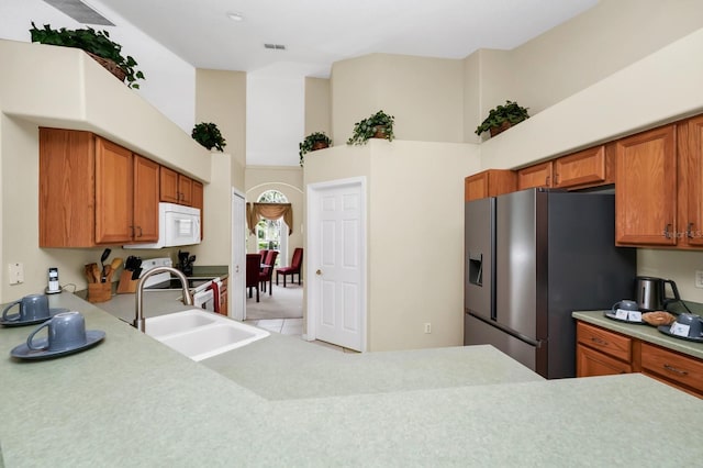 3422 Swallow Hill St, Clermont, FL 34714 - kitchen with stainless steel refrigerator with ice dispenser, a towering ceiling, white microwave, light countertops, and brown cabinets