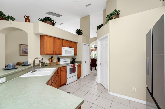 3422 Swallow Hill St, Clermont, FL 34714 - kitchen featuring white appliances, light tile patterned flooring, light countertops, a high ceiling, and brown cabinets