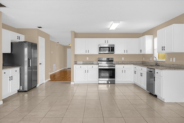 15175 Sugargrove Way, Orlando, FL 32828 - kitchen featuring appliances with stainless steel finishes, light stone counters, white cabinets, and light tile patterned floors