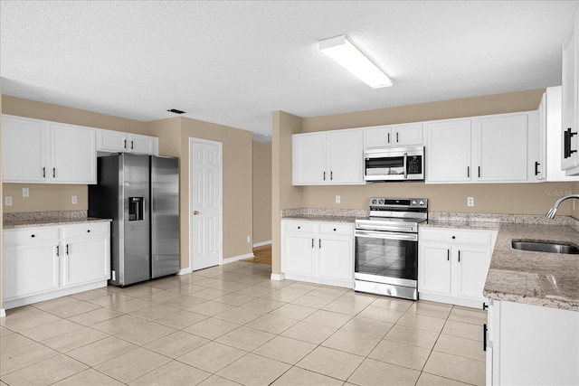 15175 Sugargrove Way, Orlando, FL 32828 - kitchen with stainless steel appliances, light stone countertops, white cabinets, a textured ceiling, and light tile patterned flooring