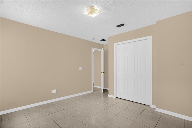 15175 Sugargrove Way, Orlando, FL 32828 - unfurnished bedroom featuring a textured ceiling, a closet, and light tile patterned floors