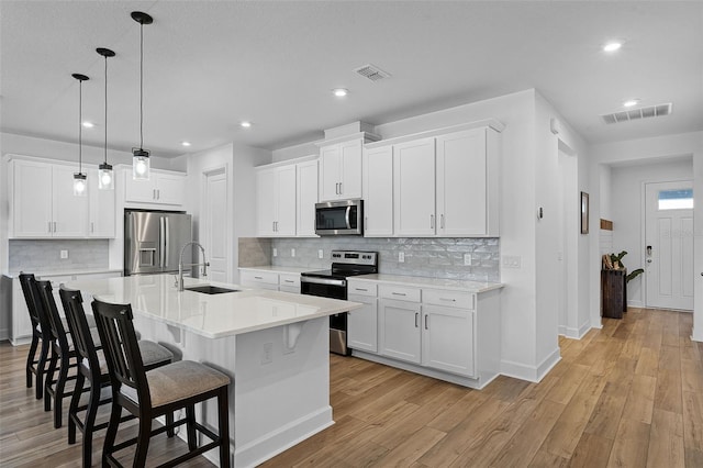 2936 Wild Mulberry Dr, Clermont, FL 34711 - kitchen with appliances with stainless steel finishes, a kitchen breakfast bar, light wood-type flooring, light countertops, and recessed lighting