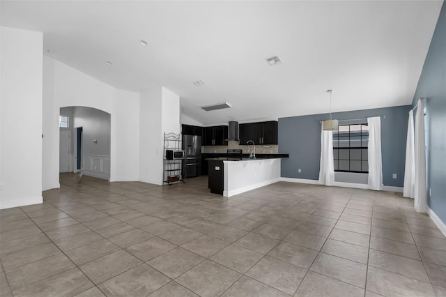 305 Chelmsford Ct, Kissimmee, FL 34758 - kitchen with open floor plan, wall chimney range hood, stainless steel appliances, arched walkways, and light tile patterned floors