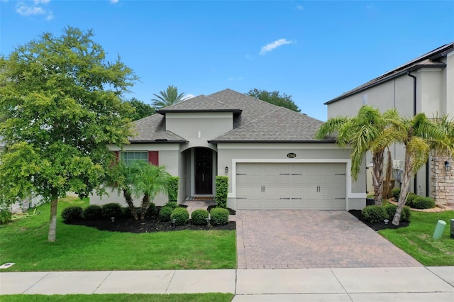 17242 Hickory Wind Dr, Clermont, FL 34711 - view of front of property with stucco siding, decorative driveway, an attached garage, and a front yard