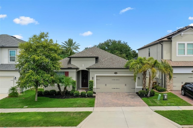 17242 Hickory Wind Dr, Clermont, FL 34711 - view of front of house with stucco siding, a shingled roof, decorative driveway, and a front lawn