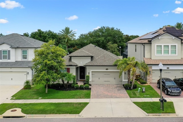 17242 Hickory Wind Dr, Clermont, FL 34711 - view of front of house with driveway, a front lawn, stucco siding, and roof mounted solar panels