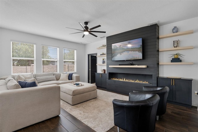 17242 Hickory Wind Dr, Clermont, FL 34711 - living room featuring a ceiling fan, dark wood-type flooring, a large fireplace, and a textured ceiling