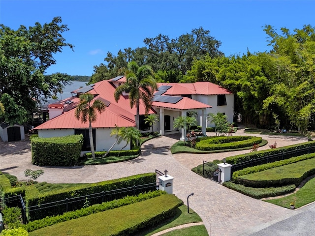 10545 Down Lakeview Cir, Windermere, FL 34786 - mediterranean / spanish house with a fenced front yard, solar panels, a metal roof, stucco siding, and decorative driveway