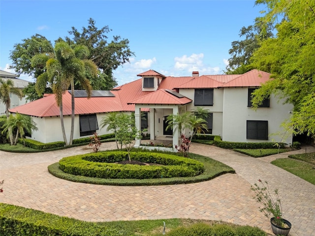 10545 Down Lakeview Cir, Windermere, FL 34786 - view of front of property featuring curved driveway, stucco siding, solar panels, a metal roof, and a chimney