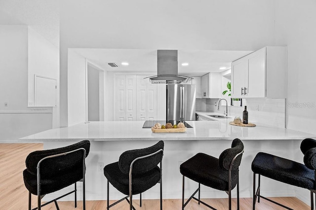 1870 Whispering Way, Tarpon Springs, FL 34689 - kitchen featuring island range hood, freestanding refrigerator, light countertops, a peninsula, and light wood-type flooring