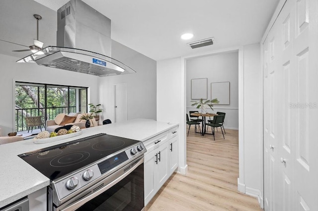 1870 Whispering Way, Tarpon Springs, FL 34689 - kitchen featuring stainless steel range with electric stovetop, island range hood, light wood finished floors, white cabinets, and recessed lighting