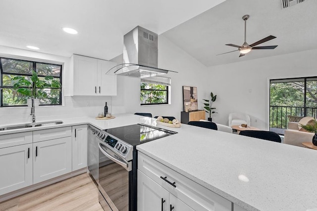 1870 Whispering Way, Tarpon Springs, FL 34689 - kitchen with island range hood, stainless steel range with electric cooktop, open floor plan, light wood-style floors, and lofted ceiling