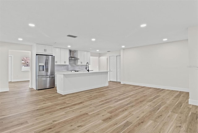 671 25th St SW, Largo, FL 33770 - kitchen featuring stainless steel fridge with ice dispenser, wall chimney exhaust hood, light countertops, light wood-type flooring, and recessed lighting