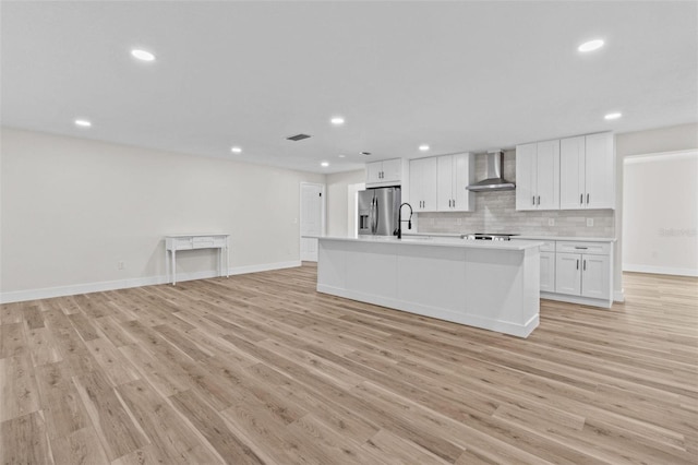 671 25th St SW, Largo, FL 33770 - kitchen featuring wall chimney exhaust hood, stainless steel fridge, white cabinets, light countertops, and open floor plan
