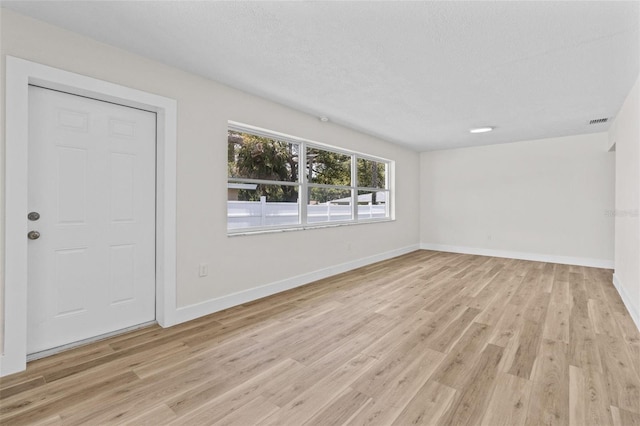 671 25th St SW, Largo, FL 33770 - spare room featuring light wood-style floors and a textured ceiling
