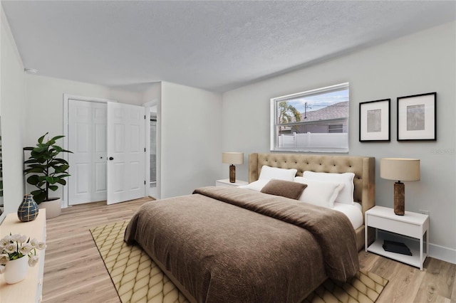 671 25th St SW, Largo, FL 33770 - bedroom with light wood-type flooring, a closet, and a textured ceiling