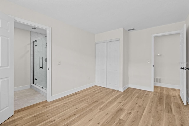 671 25th St SW, Largo, FL 33770 - unfurnished bedroom with light wood finished floors, a closet, and ensuite bathroom