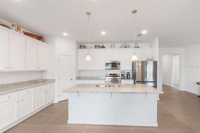 4021 Mayhill Loop, Eustis, FL 32736 - kitchen featuring stainless steel appliances, white cabinets, an island with sink, a kitchen breakfast bar, and hanging light fixtures