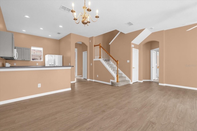 516 Brunello Dr, Davenport, FL 33897 - kitchen with white refrigerator with ice dispenser, arched walkways, light wood finished floors, a chandelier, and open floor plan