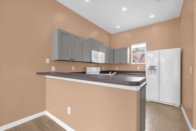 516 Brunello Dr, Davenport, FL 33897 - kitchen featuring white appliances, a peninsula, dark countertops, recessed lighting, and gray cabinetry