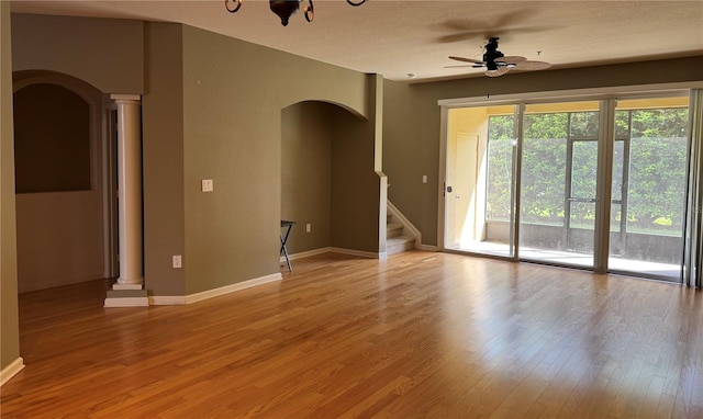 3069 Ashland Ln N, Kissimmee, FL 34741 - empty room with arched walkways, ceiling fan, light wood-style floors, stairs, and ornate columns
