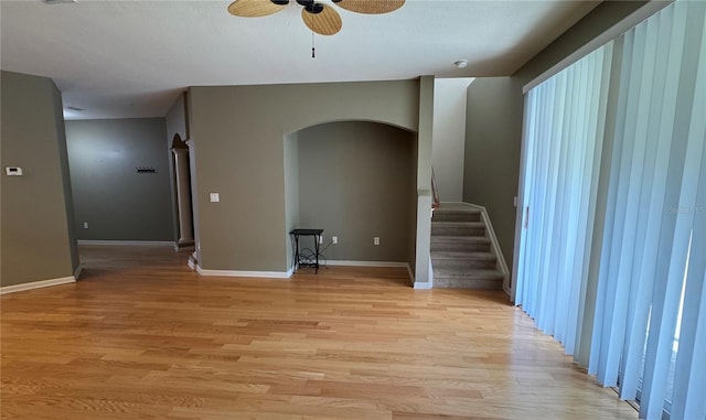 3069 Ashland Ln N, Kissimmee, FL 34741 - unfurnished living room with arched walkways, a ceiling fan, light wood finished floors, and stairs