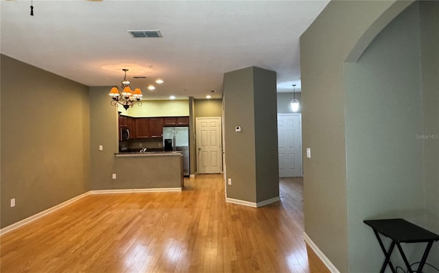 3069 Ashland Ln N, Kissimmee, FL 34741 - kitchen with appliances with stainless steel finishes, arched walkways, light wood-style flooring, a chandelier, and a peninsula