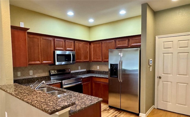 3069 Ashland Ln N, Kissimmee, FL 34741 - kitchen with stainless steel appliances, light wood finished floors, a peninsula, recessed lighting, and dark stone countertops