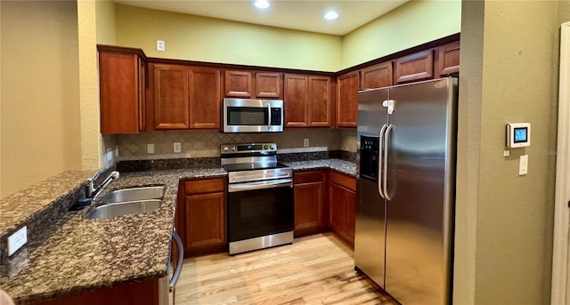 3069 Ashland Ln N, Kissimmee, FL 34741 - kitchen with appliances with stainless steel finishes, light wood finished floors, a peninsula, dark stone countertops, and recessed lighting