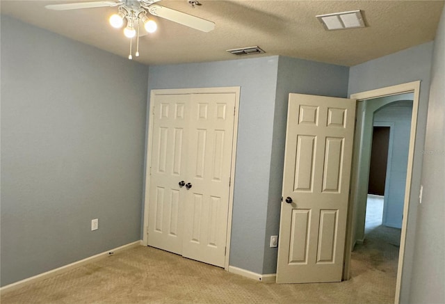 3069 Ashland Ln N, Kissimmee, FL 34741 - unfurnished bedroom featuring light colored carpet, arched walkways, a closet, and a ceiling fan