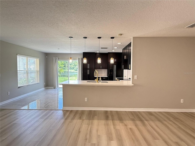 633 Flower Fields Ln, Orlando, FL 32824 - kitchen with light wood-type flooring, black fridge, open floor plan, light countertops, and a textured ceiling