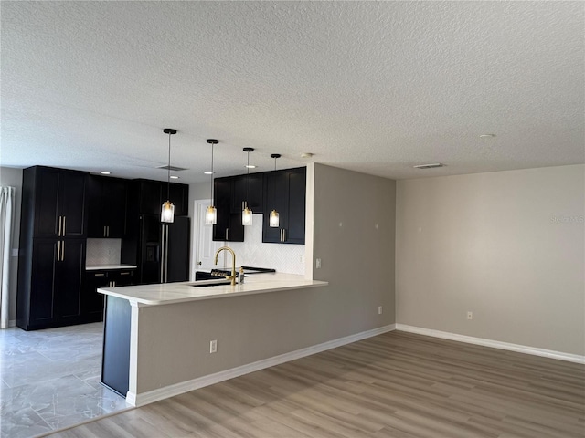 633 Flower Fields Ln, Orlando, FL 32824 - kitchen with high end black fridge, dark cabinets, a peninsula, light countertops, and a textured ceiling