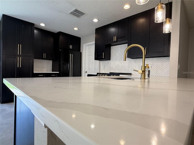 633 Flower Fields Ln, Orlando, FL 32824 - kitchen featuring black refrigerator with ice dispenser, dark cabinets, light stone counters, decorative backsplash, and recessed lighting