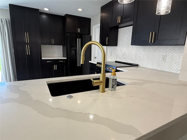 633 Flower Fields Ln, Orlando, FL 32824 - kitchen featuring dark cabinets, light stone countertops, decorative backsplash, black refrigerator with ice dispenser, and recessed lighting