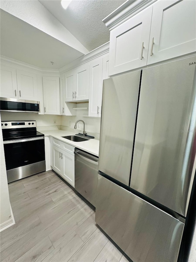6328 Raleigh St Unit 816, Orlando, FL 32835 - kitchen with appliances with stainless steel finishes, white cabinets, light countertops, lofted ceiling, and light wood-type flooring