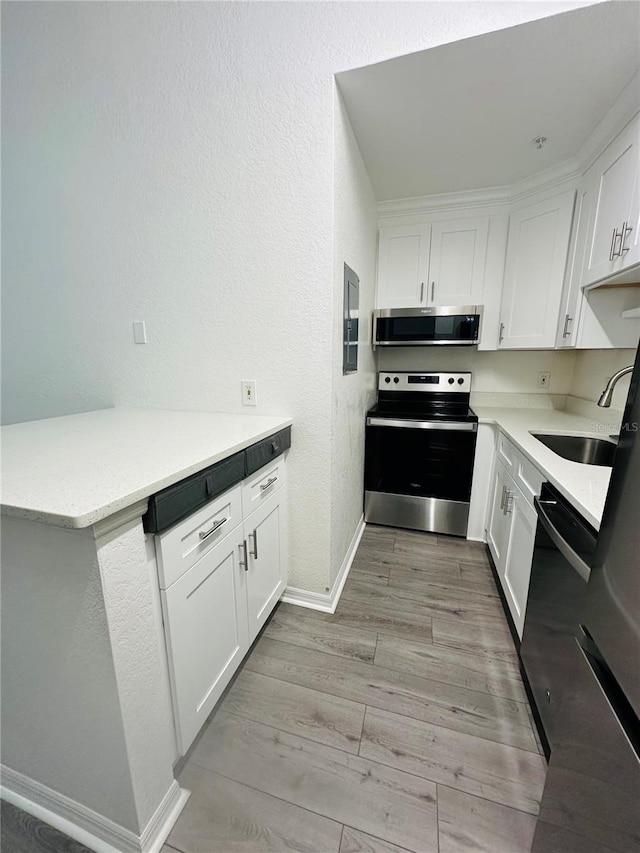6328 Raleigh St Unit 816, Orlando, FL 32835 - kitchen with appliances with stainless steel finishes, white cabinetry, light wood-style flooring, light countertops, and a textured wall