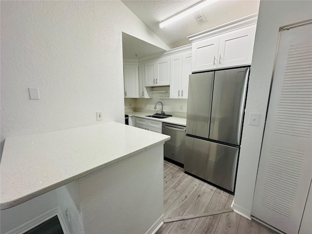6328 Raleigh St Unit 816, Orlando, FL 32835 - kitchen with stainless steel appliances, a textured wall, white cabinetry, vaulted ceiling, and light wood-style floors