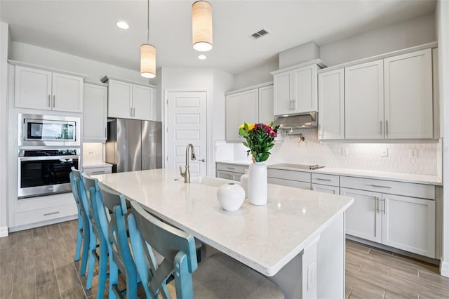 17838 Hither Hills Cir, Winter Garden, FL 34787 - kitchen with stainless steel appliances, light wood-style floors, recessed lighting, backsplash, and a breakfast bar