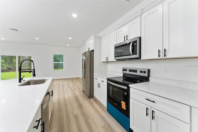 9312 N Akola Way, Citrus Springs, FL 34434 - kitchen with stainless steel appliances, light wood-style floors, white cabinets, recessed lighting, and light stone countertops